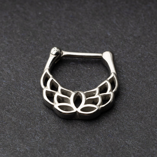 Close-up of a silver septum clicker with a lotus-inspired design, showcasing intricate petal details and a secure hinged clasp on a dark background.