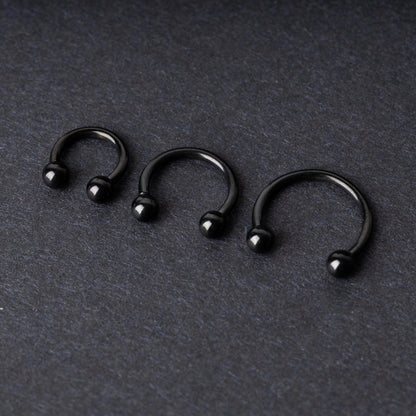 Three black stainless steel horseshoe hoops in varying sizes with threaded ball ends, displayed on a dark background.