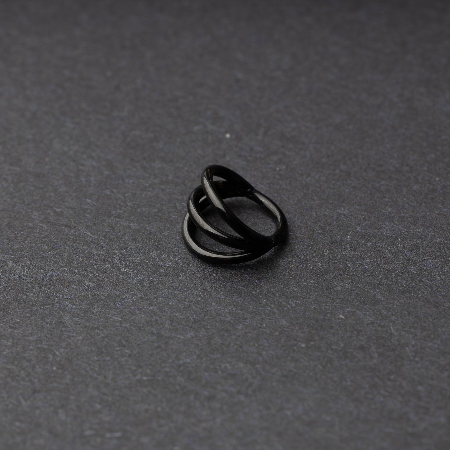 Four triple-band hoop septum clicker ring in black finish, displayed on a dark background.
