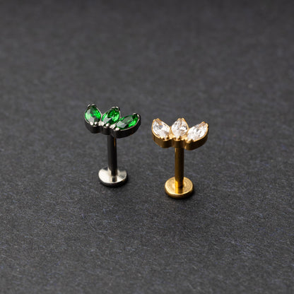 Two flat back bars featuring a triple gem design: one with emerald green gems on a silver base and the other with clear gems on a gold base, displayed on a dark background.

